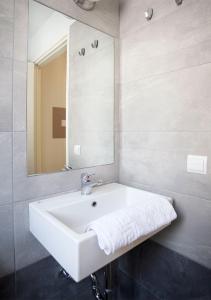 La salle de bains est pourvue d'un lavabo blanc et d'un miroir. dans l'établissement Snooze H, à Athènes