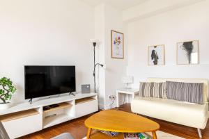 a living room with a couch and a flat screen tv at GuestReady - A minimalist comfort in Vanves in Vanves