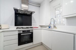 a white kitchen with a stove and a sink at GuestReady - A British charm in South Bank in London