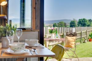 a table and chairs on a patio with a view at The Shepherds Hut in Holburn