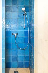 El baño incluye ducha de azulejos azules con manguera. en La Maison de B, en Lumio