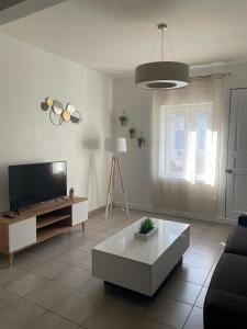ein Wohnzimmer mit Fernseher und Couchtisch in der Unterkunft Charmante maison idéalement située, centre-ville in Castres + 14 Fotos