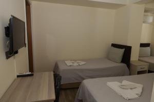 een kleine kamer met 2 bedden en een televisie bij GÜNDOĞDU OTEL in Lapseki