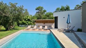 a swimming pool with chairs and an umbrella at Villa ZEL in Pazin
