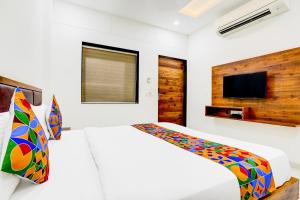 a white bedroom with a bed and a tv at FabHotel Maa Gayatri in Vadodara