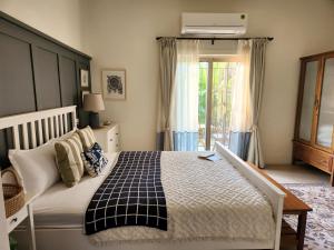 a bedroom with a bed and a window at SaffronStays Belle Maison - 3BR French style luxury villa with pool, bougainvillae views & alfresco dining near Kihim Beach in Alibaug +13 photos
