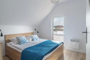 a bedroom with a bed with blue sheets and a window at Apartamenty Statki na Niebie in Rowy