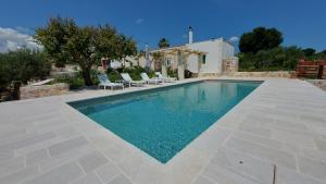 a swimming pool with chairs and a house at Casale Marangi in Locorotondo