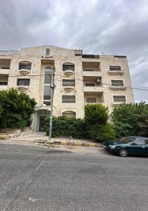 a building with a car parked in front of it at 3 rooms apartment Tlaa al ali amman شقة فاخرة 3 نوم تلاع العلي in Şāfūţ