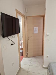 a flat screen tv hanging on a wall next to a door at Diana's Cozy 9 Studio in Ioannina