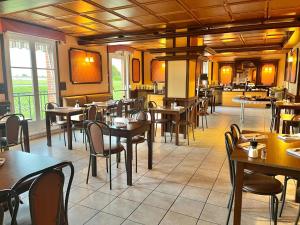 a restaurant with tables and chairs in a room at Logis Hôtel Sully le Château in Saint-Père-sur-Loire