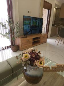 a living room with a vase with flowers in front of a tv at Agora Luxury Villa I in Loutraki