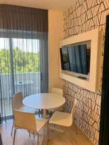 a dining room with a table and chairs and a tv at Astoria Suite Hotel in Rimini