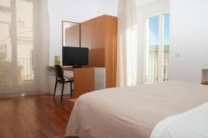 um quarto com uma cama e uma secretária com uma televisão em Hotel La Dimora di Piazza Carmine em Ragusa