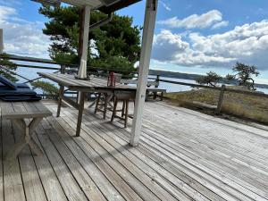 een houten terras met een picknicktafel en uitzicht op het water bij Seaside Bliss for Families: Home Away from Home in Stavsnäs