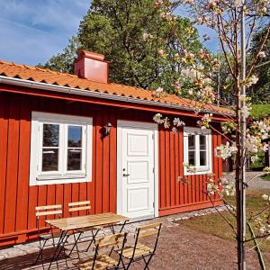 una cabina roja con una mesa y sillas frente a ella en Korskullens Stugor, en Söderköping