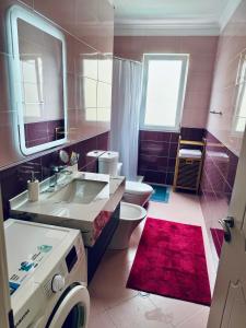 a bathroom with a white toilet and a sink and a sink at Sunset Appartment in Golem