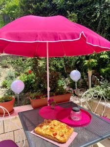 uma pizza sentada numa mesa debaixo de um guarda-chuva cor-de-rosa em Rooms Villa Gala em Mlini