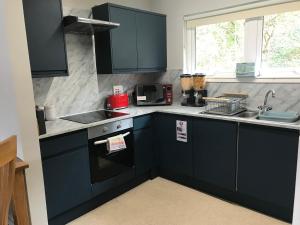 a kitchen with dark blue cabinets and a sink at Borrodale, one bedroom apartment with balcony and loch view. in Fort William