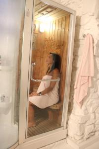 uma mulher sentada num chuveiro na casa de banho em CR La Posada de los Sentidos em Jarandilla de la Vera