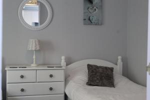 een slaapkamer met een bed, een dressoir en een spiegel bij Salty Air - Mount Brioni in Downderry