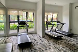 a gym with three treadmills in a room with windows at Cozy Beach Escape: 2BR Muji Gem in Johor Bahru