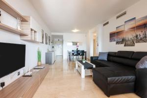 a living room with a black couch and a flat screen tv at Aguamarina Gamonal in Marbella