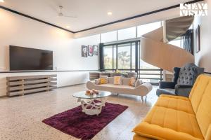 a living room with a couch and a tv at StayVista at Dreamsville Apartment with Pet-friendly, Bathtub in Alibaug