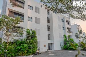 a white building with trees in front of it at StayVista at Dreamsville Apartment with Pet-friendly, Bathtub in Alibaug