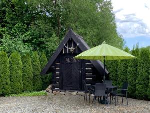 a black out house with chairs and an umbrella at Alpina in Krynica Zdrój