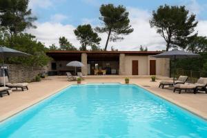 Una piscina con sillas y sombrillas al lado de una casa. en Lou Recati La Ribelle En Provence, en LʼIsle-sur-la-Sorgue