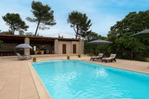 a swimming pool with chairs and umbrellas on a patio at Lou Recati La Ribelle En Provence in Saumane-de-Vaucluse