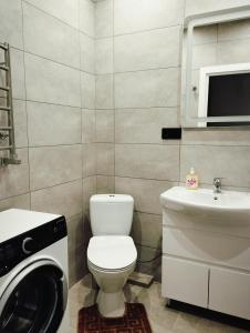 uma casa de banho com um WC, um lavatório e uma máquina de lavar roupa em VIP квартира однокімнатна em Lutsʼk