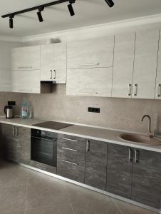 uma cozinha com armários brancos e um lavatório em VIP квартира однокімнатна em Lutsʼk