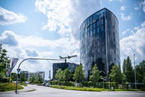 an airplane is flying in front of a glass building at Airport Plaza Hotel Hamburg in Norderstedt