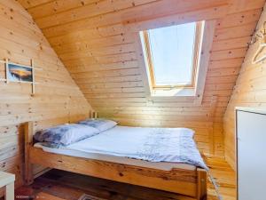 uma cama num quarto de madeira com uma janela em Domki nad morzem Kąty Rybackie em Kąty Rybackie