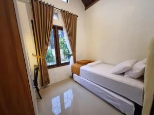 a bedroom with two beds and a window at House of Pringgitan in Ngemplak