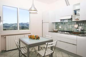 カポリーヴェリにあるLo Scoglio - Goelbaの白いキャビネット、テーブルと椅子付きのキッチンが備わります。