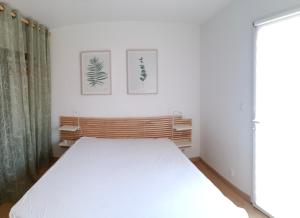un letto bianco in una stanza con due immagini sul muro di Les gîtes aux portes de Saint-Quay-Portrieux a Plourhan