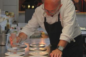 Ein Mann in einer Küche, der Teller auf einer Theke zubereitet. in der Unterkunft Bella Vista Hôtel, Suites & Maisons in Porticcio