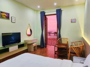 Schlafzimmer mit einem Bett, einem TV und einem Balkon in der Unterkunft Sunset Hotel Phu Quoc - welcome to a mixing world of friends in Phu Quoc
