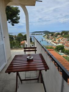 een houten tafel op een balkon met uitzicht op een rivier bij Apartmani Nata in Maslinica