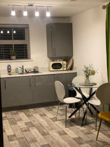 cocina con mesa, sillas y microondas en Peterborough City Center One Bed apartment With Free Private Parking en Peterborough