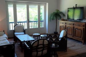 a living room with a tv and a table and chairs at Charmante maison familiale avec jardin et jacuzzi proche océan in Saint-Martin-de-Seignanx