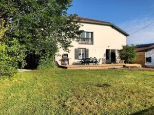 a house with a wooden deck in front of a yard at Charmante maison familiale avec jardin et jacuzzi proche océan in Saint-Martin-de-Seignanx