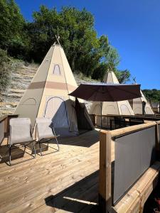聖塞巴斯提安的住宿－宜佳拉聖塞巴斯蒂安露營地，帐篷、2把椅子和1张带雨伞的桌子