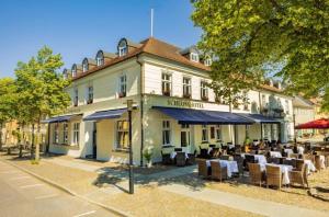 um restaurante com mesas e cadeiras em frente a um edifício em Schlosshotel Rheinsberg em Rheinsberg