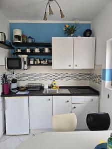 - une cuisine avec des placards blancs et un évier dans l'établissement Apartmani Nata, à Maslinica