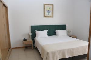 a bedroom with a large bed with a green headboard at Hotel Santa Catarina Algarve in Portimão