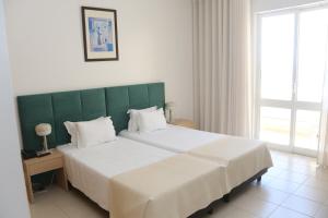 a bedroom with a large bed with a green headboard at Hotel Santa Catarina Algarve in Portimão